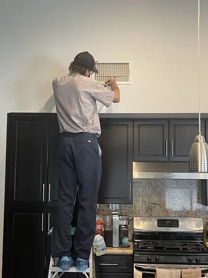 Technician inspecting an air vent during HVAC service in Kalispell